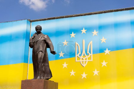 Die Statue der herausragenden ukrainischen Persönlichkeit Taras Schewtschenko befindet sich vor dem Hintergrund einer hellen ukrainischen Flagge. Strahlend sonniges Wetter steigert den optischen Reiz der Szene.