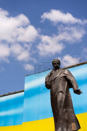 La estatua de una figura ucraniana excepcional Taras Shevchenko se encuentra en el fondo de una brillante bandera ucraniana. Clima soleado brillante mejora el atractivo visual de la escena.