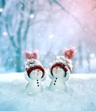 Photo for Merry christmas and happy new year greeting card. Happy two little snowmen in cap standing in winter snow background. - Royalty Free Image