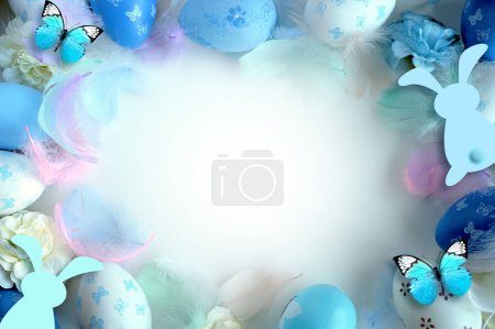 Foto de Concepto de decoraciones de Pascua. Foto de vista superior de huevos de Pascua coloridos, flores y plumas azules sobre fondo azul pastel aislado. - Imagen libre de derechos