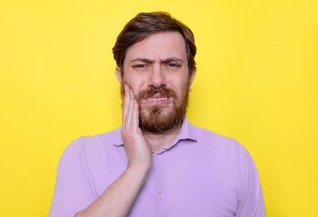 Male feeling pain and toothache, holding his cheek with hand
