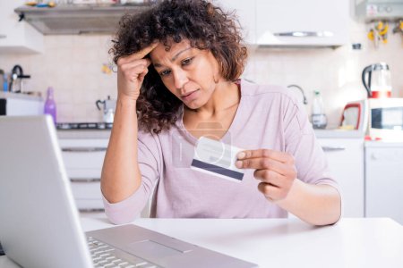 Doubtful black woman using credit card for online shopping