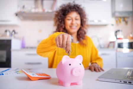 Smiling black woman saving goal for future retirement plan, focus on piggy bank