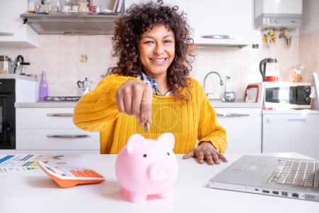 Téléchargez les photos : Cheerful black woman saving money for the future looking at the camera - en image libre de droit