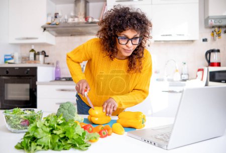 Photo for Happy black woman learning to cook at home with online courses - Royalty Free Image