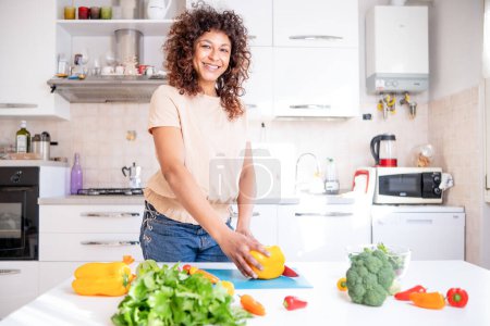 Photo for Happy black woman ready to cook in domestic kitchen looking a the camera - Royalty Free Image