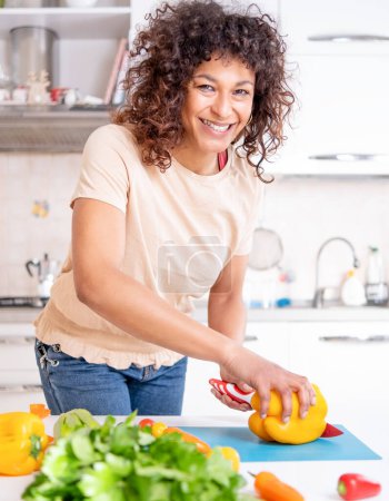 Photo for Cheerful black woman cooking at home looking a the camera - Royalty Free Image