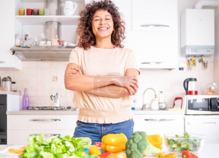 Photo for Cheerful black woman cooking at home looking a the camera - Royalty Free Image