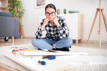 Téléchargez les photos : Femme éprouvant frustration et stress tout en essayant d'assembler des meubles pour un projet de rénovation domiciliaire. - en image libre de droit