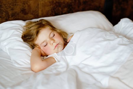 Photo for Cute little toddler girl sleeping in bed. Adorable baby child dreaming, healthy sleep of children by day. Deep sleeping of toddler. Kids resting - Royalty Free Image