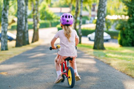 Foto de Niña preescolar con casco corriendo con bicicleta de equilibrio en el día de verano. Feliz niño conduciendo, ciclismo con bicicleta, actividad al aire libre. Felicidad, infancia. Actividad de verano para niños - Imagen libre de derechos