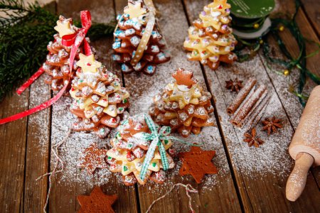 Photo for Home made baked Christmas gingerbread tree as a gift for family and friends on wooden background. With colorful lights from Christmas tree on background. With icing sugar gift for xmas. - Royalty Free Image