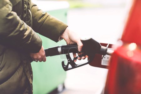 Photo for Close-up of hands of woman at self-service gas station, hold fuel nozzle and refuel the car with petrol, diesel, gas. Close up of filling auto with gasoline or benzine. Self service gas pump. - Royalty Free Image