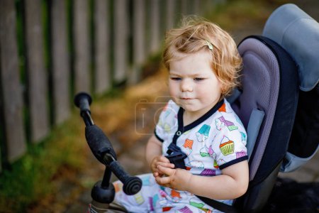 Photo for Cute adorable toddler girl sitting on pushing bicyle or tricycle. Little baby child going for a walk with parents on sunny day. Happy healthy kid in colorful clothes. - Royalty Free Image