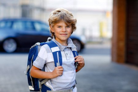 Foto de Niño feliz con mochila o mochila llamada Ranzen en alemán. Un colegial de camino a la escuela. Retrato de niño sano adorable al aire libre. Estudiante, alumno, de vuelta a la escuela. Edad de la escuela primaria. - Imagen libre de derechos