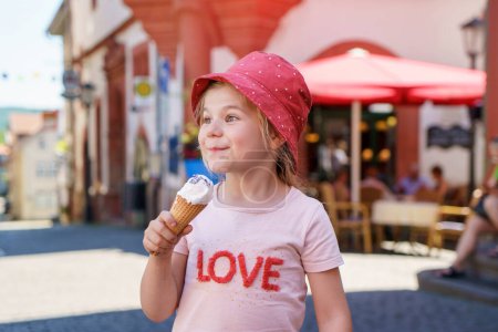 Foto de Hermosa niña come helado en el verano. Feliz chica divertida preescolar con cono de helado dulce en la ciudad - Imagen libre de derechos