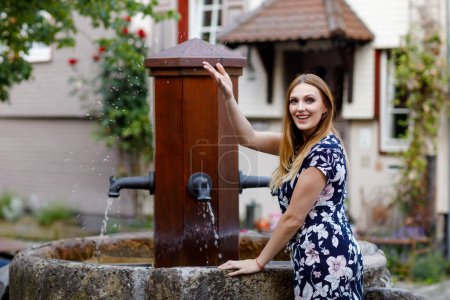 Photo for Beautiful young woman with long hairs in summer dress going for a walk in German city. Happy girl enjoying walking in cute small fachwerk town with old houses in Germany - Royalty Free Image