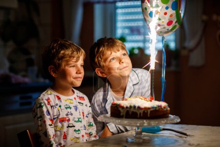 Photo for Two beautiful kids, little preschool boys celebrating birthday and blowing candles on homemade baked cake, indoor. Birthday party for siblings children. Happy twins about gifts and fireworks on tarte. - Royalty Free Image