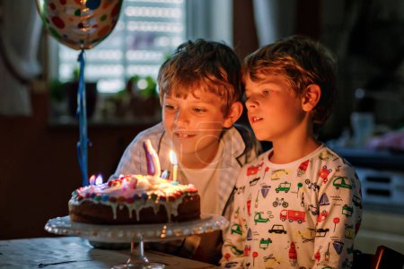 Photo for Two beautiful kids, little preschool boys celebrating birthday and blowing candles on homemade baked cake, indoor. Birthday party for siblings children. Happy twins about gifts and fireworks on tarte. - Royalty Free Image