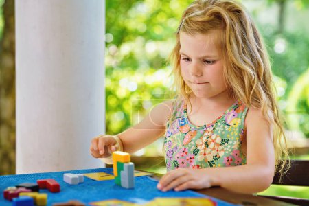 Photo for Little preschool girl playing board game with colorful bricks. Happy child build tower of wooden blocks, developing fine motor skills, home joint games. Leisure activities for children at home - Royalty Free Image