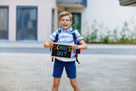 Téléchargez les photos : Joyeux petit garçon avec sac à dos ou sacoche. Un écolier en route pour l'école. Enfant adorable en bonne santé à l'extérieur Avec bureau à craie pour copyspace. Retour à l'école ou à l'école - en image libre de droit