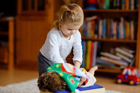 Photo for Adorable cute little toddler girl playing with doll. Happy healthy baby child having fun with role game, playing mother at home or nursery. Active daughter with toy. - Royalty Free Image