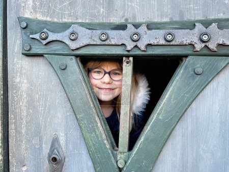 Téléchargez les photos : Portrait d'une petite fille avec des lunettes dans une maison de jeux en bois pour enfants - en image libre de droit