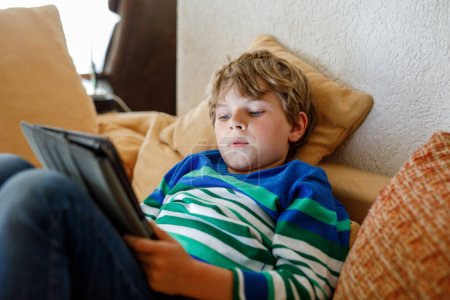 Photo for School boy with tablet computer. Schoolchild study online. Electronic device for learning, studying and playing at home. Little boy with laptop pc. Gadget and screen time for children. Kid at home - Royalty Free Image