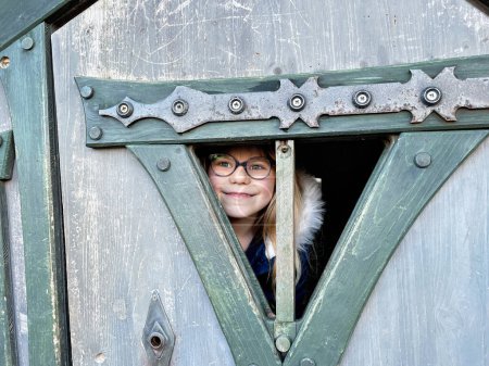 Photo for Portrait of a little girl with eye glasses in wooden house of playground for children - Royalty Free Image