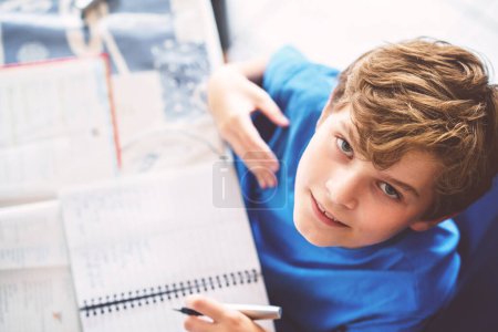 Téléchargez les photos : Un jeune garçon qui fait ses devoirs à la maison. Apprentissage scolaire - en image libre de droit