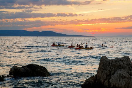 Téléchargez les photos : Kayaker pagayant le kayak au coucher du soleil mer. Kayak, canot, pagaie. Coucher de soleil incroyable sur la plage avec un horizon sans fin et d'incroyables vagues mousseuses - en image libre de droit
