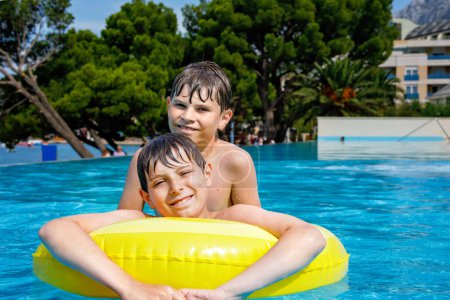 Photo for Two kids boys having fun on inflatable rubber rings in outdoor pool. Summer holiday. Summertime kids weekend. Children having fun, brothers on family vacations - Royalty Free Image