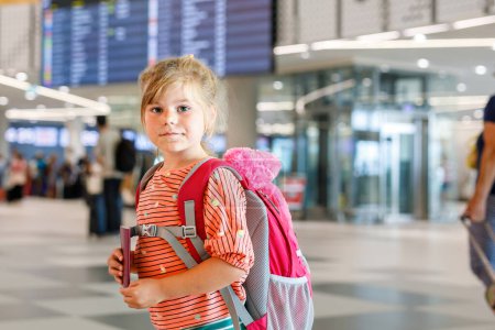 Photo for Little preschool girl at airport terminal. Happy child going on vacations by airplane. Smiling kid with passport and bag - Royalty Free Image