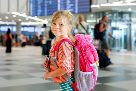 Téléchargez les photos : Petite fille d'âge préscolaire à l'aéroport. Joyeux enfant en vacances en avion. Enfant souriant avec passeport et sac - en image libre de droit