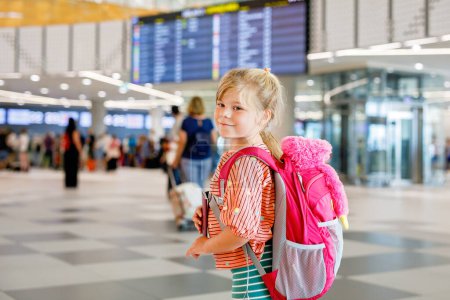 Téléchargez les photos : Petite fille d'âge préscolaire à l'aéroport. Joyeux enfant en vacances en avion. Enfant souriant avec passeport et sac - en image libre de droit