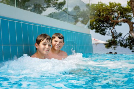 Téléchargez les photos : Deux enfants garçons s'amusent dans la piscine extérieure. Vacances d'été. Week-end d'été pour enfants. Enfants qui s'amusent, frères en vacances en famille - en image libre de droit