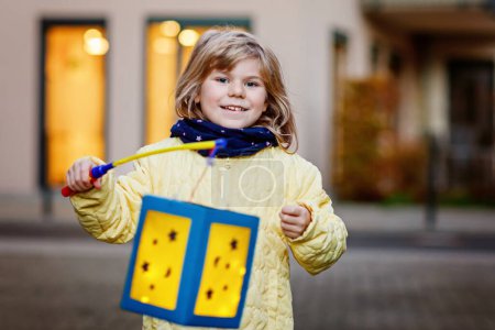 Photo for Little preschool kid girl holding selfmade traditional lanterns with candle for St. Martin procession. child happy about children and family parade in kindergarten. German tradition Martinsumzug. - Royalty Free Image