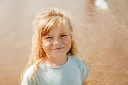 Foto de Feliz niña preescolar divirtiéndose en la playa de arena Omaha en la costa atlántica de Normandía, Francia. Actividades de verano al aire libre para niños. - Imagen libre de derechos