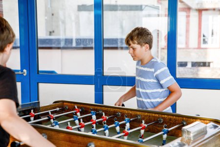 Photo for Two smiling school boys playing table soccer. Happy excited children having fun with family game with siblings or friends. Positive preteen kids or teenager - Royalty Free Image
