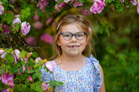 Téléchargez les photos : Portrait d'une jolie fille d'âge préscolaire avec des lunettes à l'extérieur dans le parc. Heureux enfant drôle le jour ensoleillé d'été - en image libre de droit