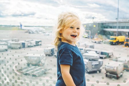 Photo for Cute little toddler girl at the airport, traveling. Happy healthy child waiting near window and watching airplanes. Family going on summer vacations by plane - Royalty Free Image