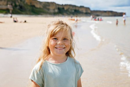 Photo for Happy preschool girl having fun on the sand beach Omaha at Atlantic coast of Normandy, France. Outdoor summer activities for kids. - Royalty Free Image