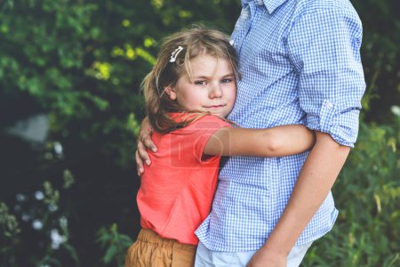 Photo for An upset little girl finds comfort in the embrace of her caring teenage brother, exemplifying the bond of a loving family. Loving Siblings, Brother and Sister - Royalty Free Image