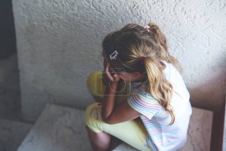 Foto de Lonely Upset Little Preschool Girl at Home (en inglés). Triste niño solo. Estrés emocional de los niños, la escuela y los problemas familiares - Imagen libre de derechos