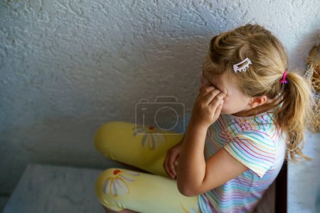 Foto de Lonely Upset Little Preschool Girl at Home (en inglés). Triste niño solo. Estrés emocional de los niños, la escuela y los problemas familiares - Imagen libre de derechos