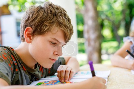 Foto de Preteen School Boy Drawing with Felt Pens (en inglés). De vuelta a la escuela. Pequeño colegial caucásico dibujo en casa. Hobby, Concepto Educativo - Imagen libre de derechos