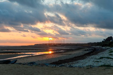 Téléchargez les photos : Vue du lever du soleil sur la rue côtière de Grandcamp Maisy, une ville côtière française pittoresque en Normandie, avec port de pêche, plages de sable fin et traditions maritimes - en image libre de droit