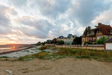 Foto de Vista del amanecer de la calle costera del Grandcamp Maisy, una pintoresca ciudad costera francesa en Normandía, con puerto pesquero, playas de arena y tradiciones marítimas - Imagen libre de derechos