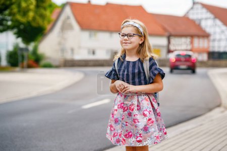 Photo for Little Preschool Girl on the Way to School. Healthy Happy Child Walking to Nursery School and Kindergarten. Smiling Child with Eyeglasses and Backpack on the City Street, Outdoors. Back to School - Royalty Free Image