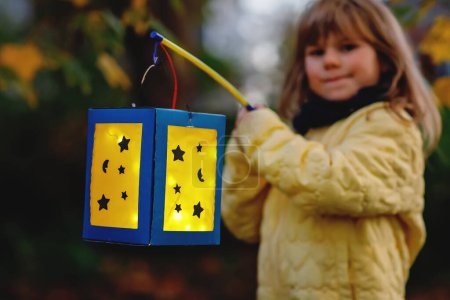Photo for Closeup of little preschool kid girl holding selfmade traditional lanterns with candle for St. Martin procession. child happy about family parade in kindergarten. German tradition Martinsumzug. - Royalty Free Image